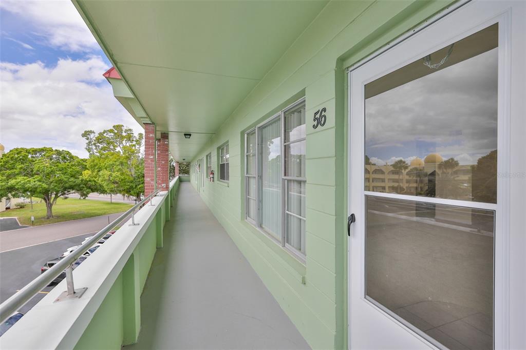 An exterior walkway with a green wall, a numbered door, and a metal railing — 2358 ECUADORIAN WAY UNIT 56, CLEARWATER, FL