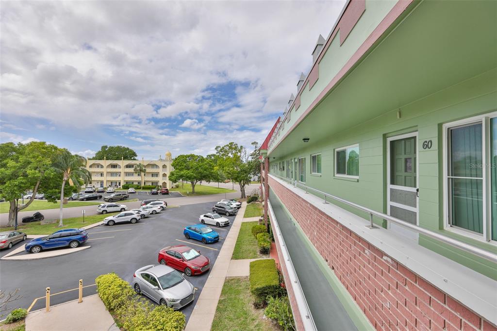 An exterior view of a multi-story apartment building with a walkway and parking lot — 2358 ECUADORIAN WAY UNIT 56, CLEARWATER, FL