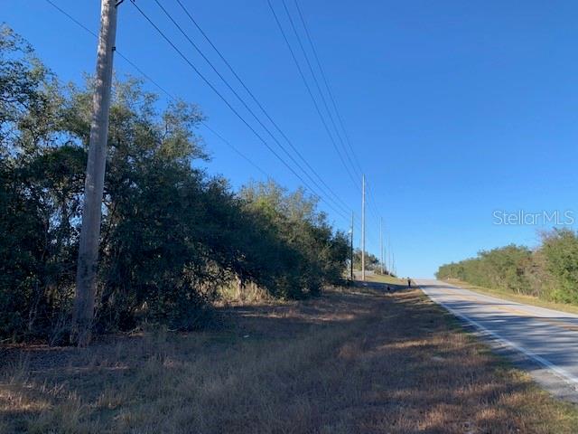 A paved road runs alongside a grassy area with trees and utility poles — 3288 MASTERPIECE ROAD, LAKE WALES, FL