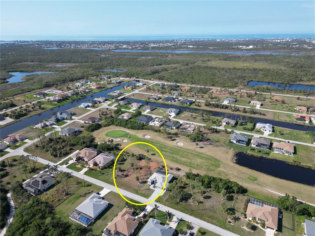 An aerial view shows a vacant residential lot highlighted by a yellow circle on a golf course — 10 PINE VALLEY PLACE, ROTONDA WEST, FL
