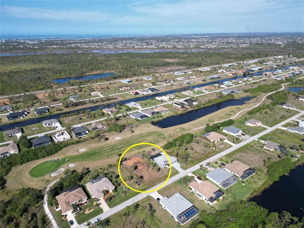 An aerial view shows a vacant residential lot highlighted in yellow within a golf course community — 10 PINE VALLEY PLACE, ROTONDA WEST, FL