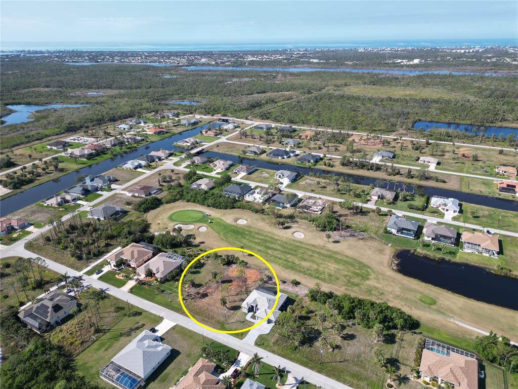 An aerial view shows a vacant residential lot next to a house on a golf course — 10 PINE VALLEY PLACE, ROTONDA WEST, FL