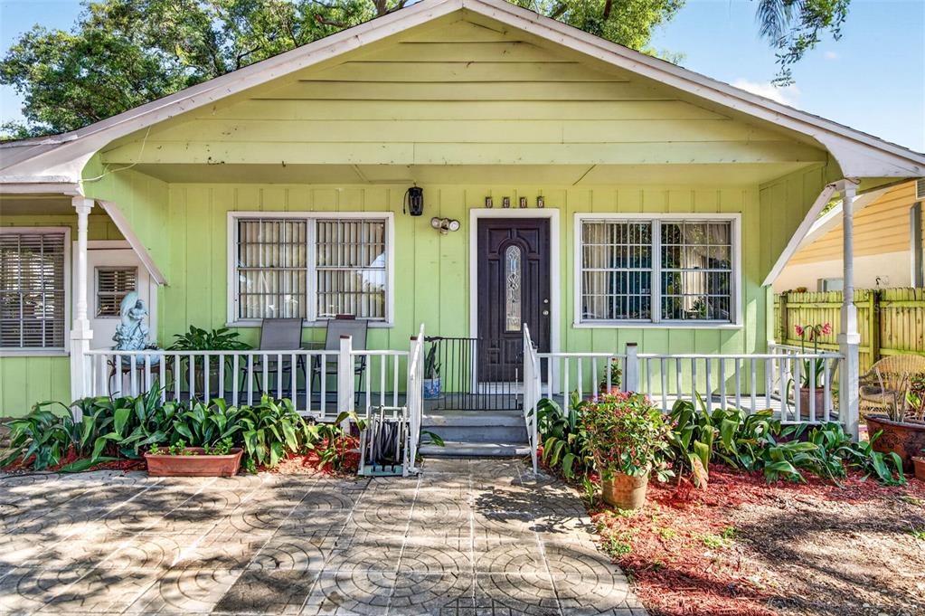A light green house with a front porch, dark door, and paved patio area — 1417 W YUKON STREET, TAMPA, FL