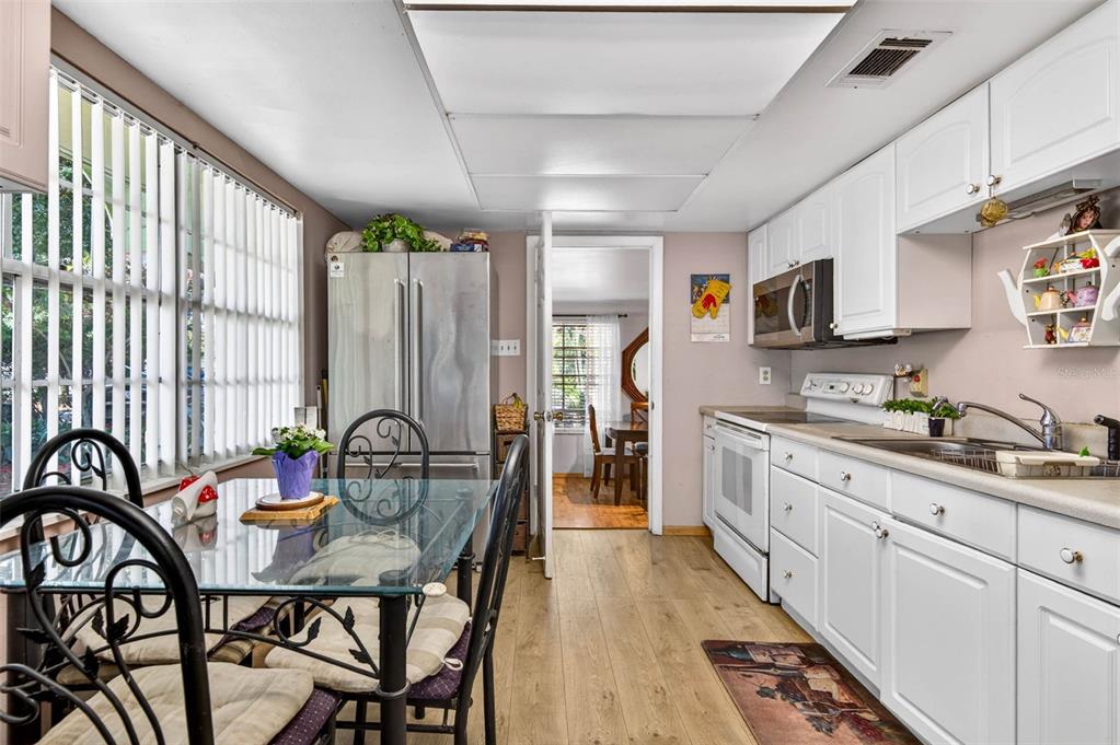 A kitchen with white cabinets, stainless steel appliances, and a glass-topped dining table — 1417 W YUKON STREET, TAMPA, FL