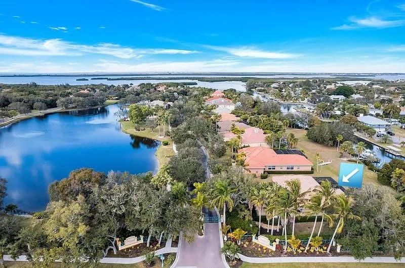 An aerial view shows a residential neighborhood with houses, palm trees, and a large lake — 1704 AMBERWYND CIRCLE W, PALMETTO, FL
