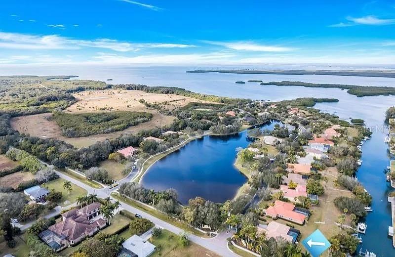 An aerial view shows a residential neighborhood surrounding a lake near a coastal waterway — 1704 AMBERWYND CIRCLE W, PALMETTO, FL