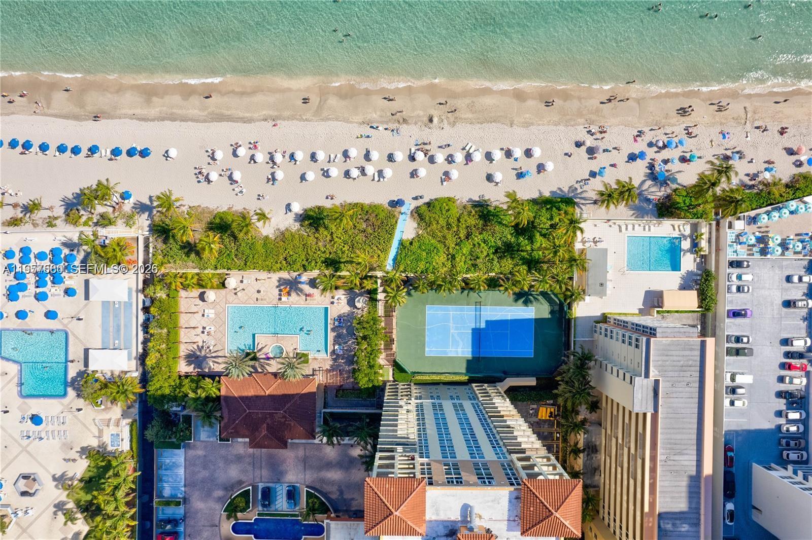 An aerial view shows a high-rise building with pools, a tennis court, and beach access — 2080 S Ocean Dr # 506, Hallandale Beach FL 33009, HALLANDALE BEACH, FL