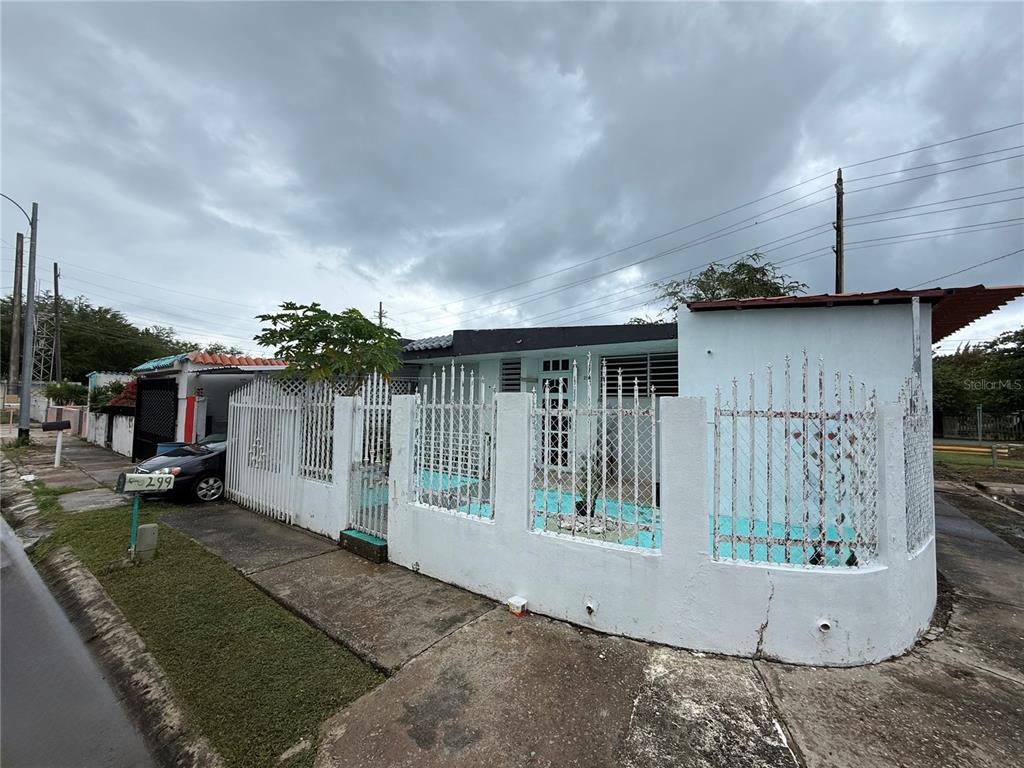 A white concrete house features a metal security fence and a small front courtyard — . 13 UNIT 299, PUNTA SANTIAGO, PR