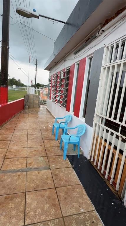 A tiled outdoor patio features two blue plastic chairs against a red and white wall — . 13 UNIT 299, PUNTA SANTIAGO, PR