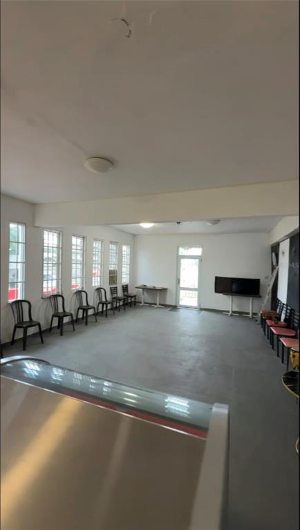 A spacious, empty room with gray flooring, multiple windows, and rows of chairs — . 13 UNIT 299, PUNTA SANTIAGO, PR