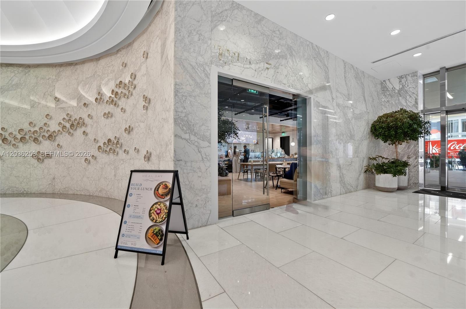 A marble-walled restaurant entrance features a glass door and a menu stand on tile flooring — 2 S Biscayne Blvd, Miami FL 33131, MIAMI, FL