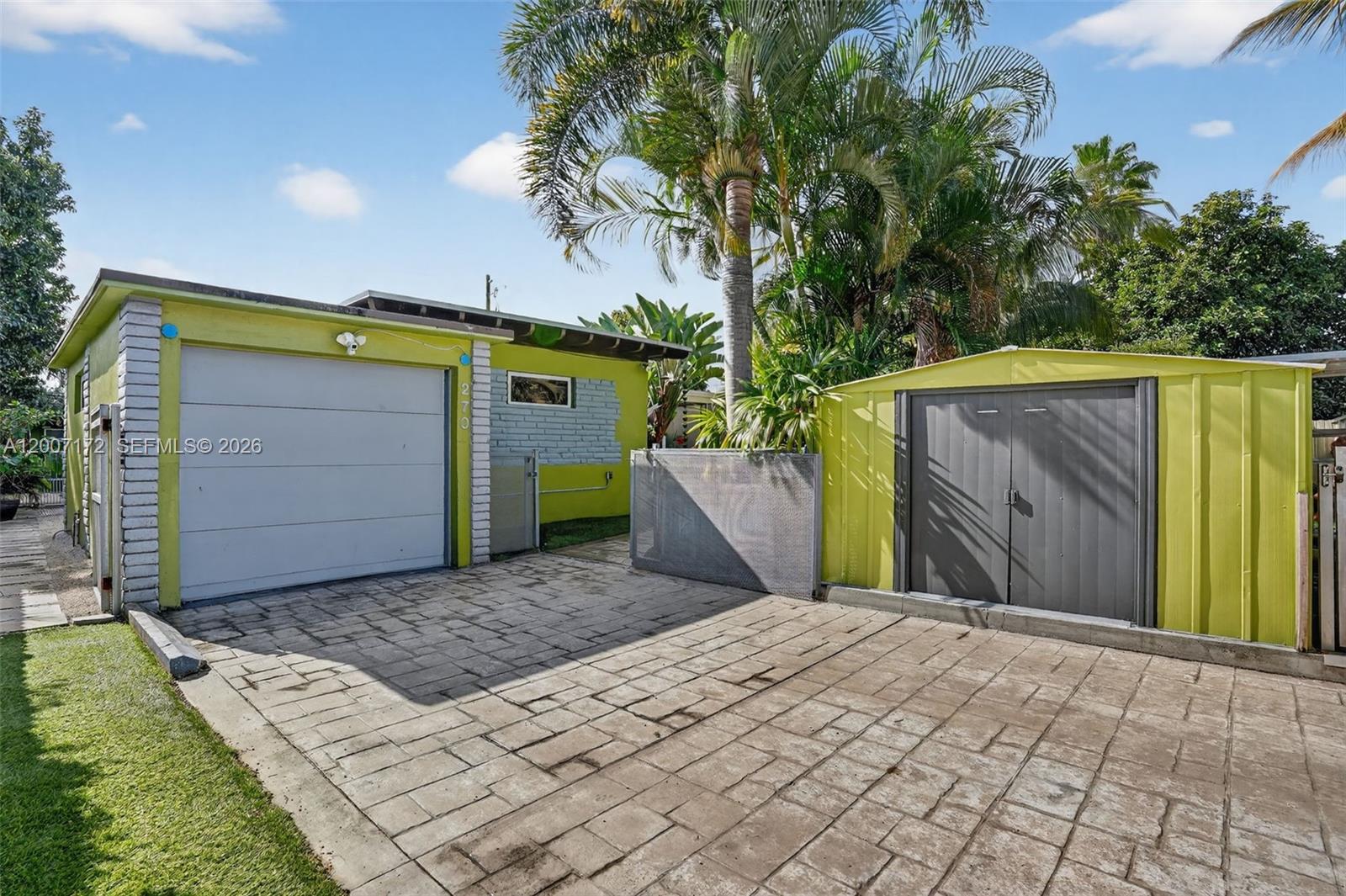 A lime green garage and matching storage shed sit on a paved driveway — 270 NW 106th St, Miami FL 33150, MIAMI, FL