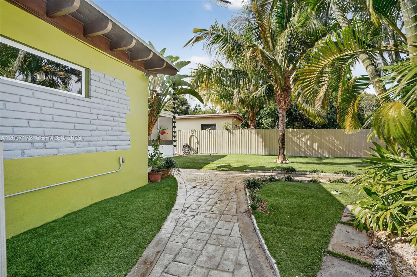 A lime green house exterior features a brick accent wall, stone walkway, and palm trees — 270 NW 106th St, Miami FL 33150, MIAMI, FL