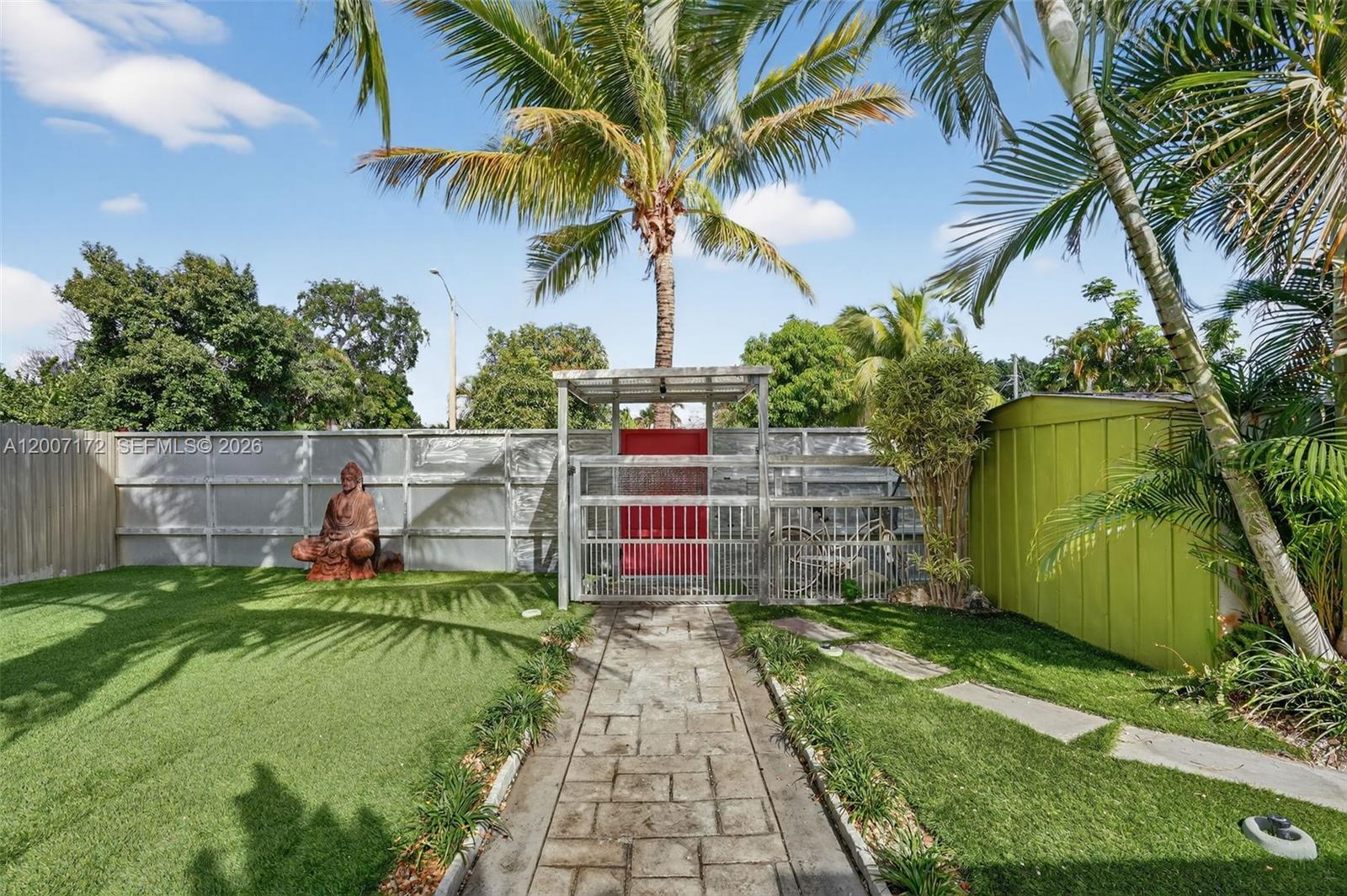A stone walkway leads to a gated entrance in a fenced backyard with artificial turf — 270 NW 106th St, Miami FL 33150, MIAMI, FL