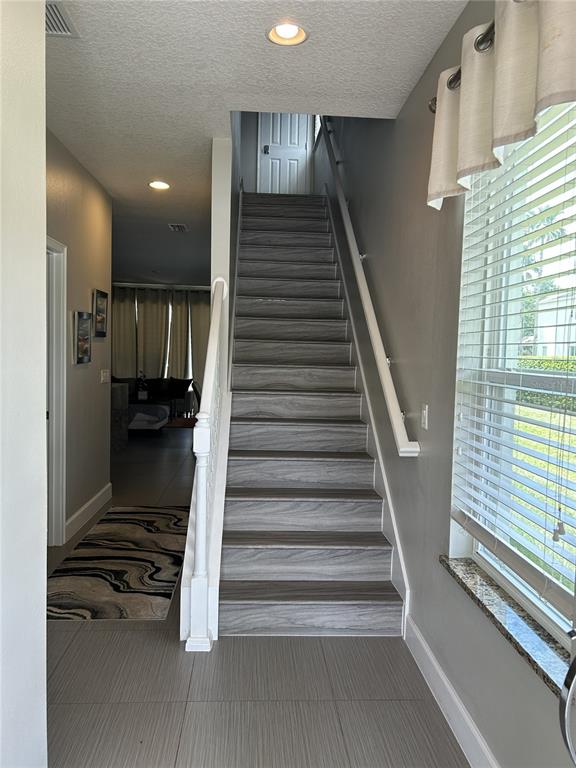 An interior view shows a staircase with wood-look treads leading to an upper landing — 1421 RETREAT CIRCLE, CLERMONT, FL