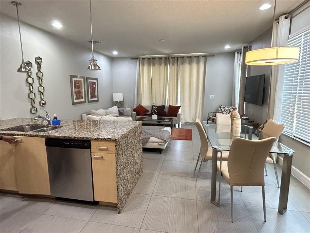 An open-concept kitchen and living area features granite countertops, tile flooring, and a dining set — 1421 RETREAT CIRCLE, CLERMONT, FL