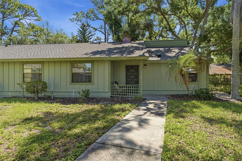 A single-story house with green vertical siding, a dark front door, and a concrete walkway — 5080 BARRINGTON CIRCLE UNIT 3102, SARASOTA, FL