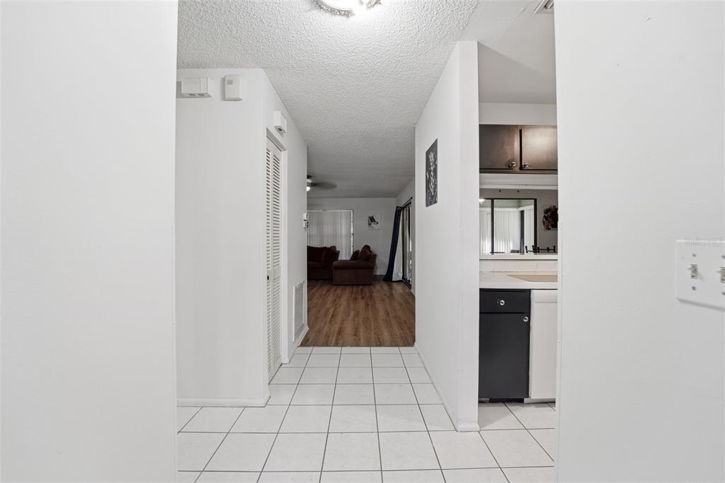 A tiled entryway leads into a living area with wood-look flooring and a kitchen — 5080 BARRINGTON CIRCLE UNIT 3102, SARASOTA, FL