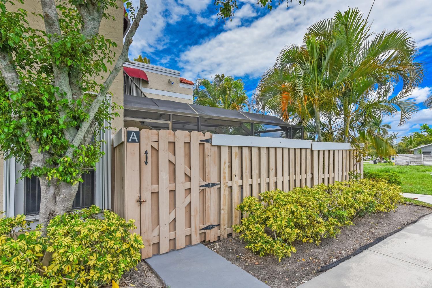 A wooden gate with an A label leads to a screened patio beside a building — 3640 Village Drive # A, Delray Beach FL 33445, DELRAY BEACH, FL