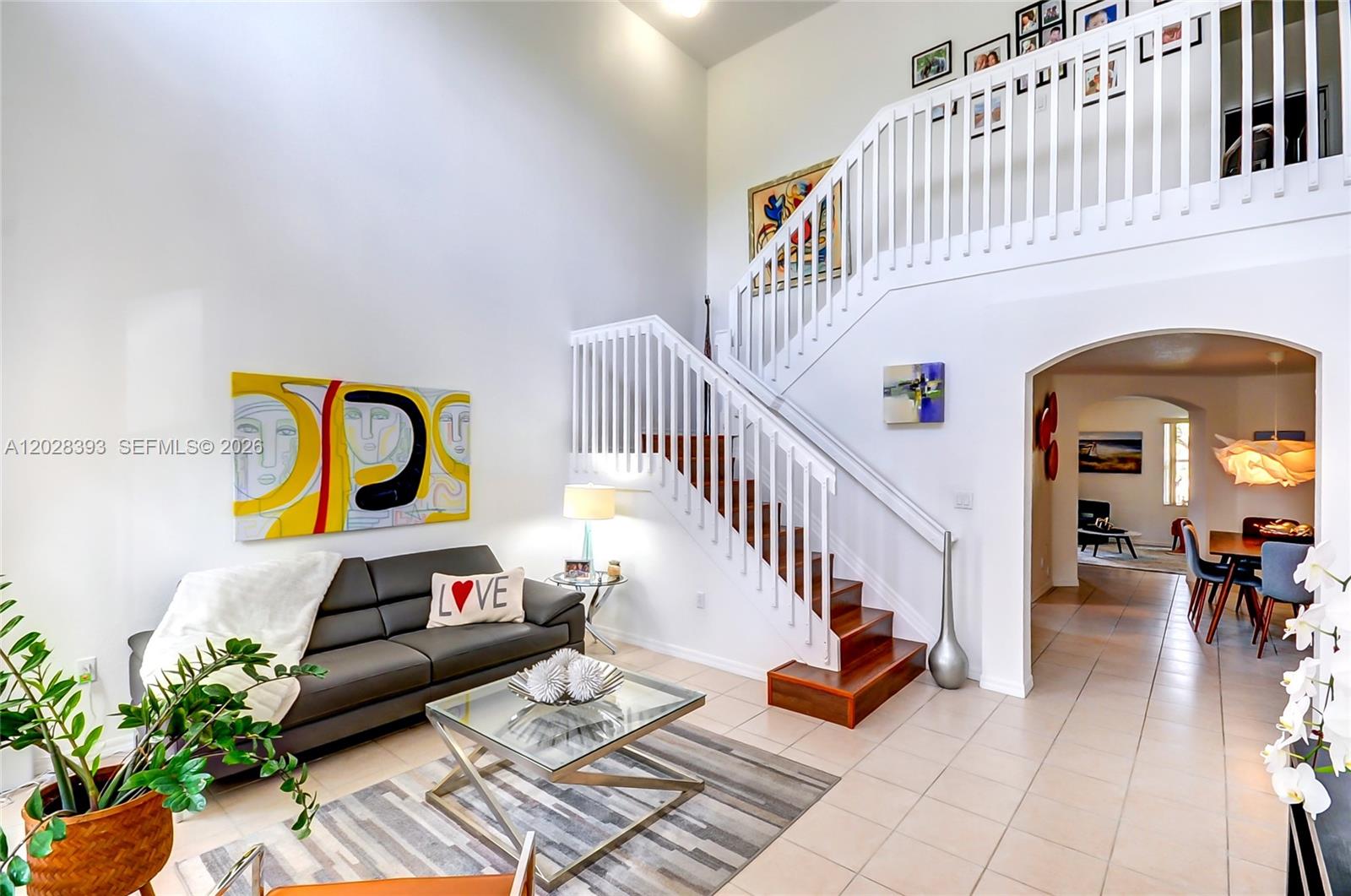 A living room features a dark sofa, a glass coffee table, and a wooden staircase — 16600 SW 47th Ter, Miami FL 33185, MIAMI, FL