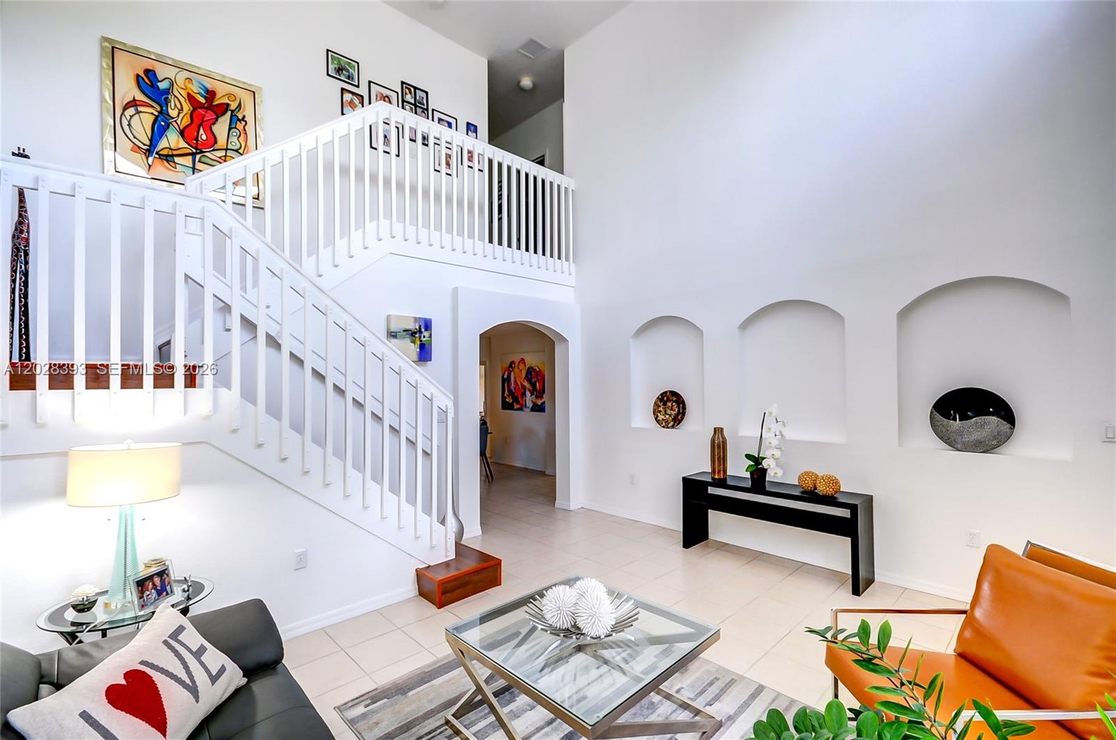 A bright living room features a white staircase, arched wall niches, and modern furniture — 16600 SW 47th Ter, Miami FL 33185, MIAMI, FL