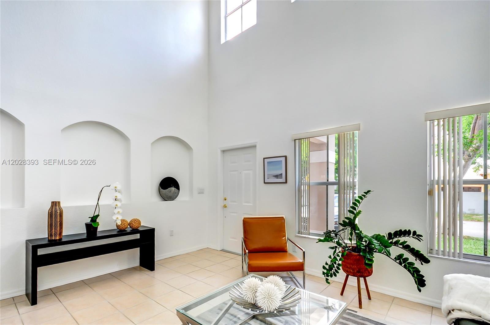 A bright living room features high ceilings, tiled floors, arched wall niches, and a glass table — 16600 SW 47th Ter, Miami FL 33185, MIAMI, FL