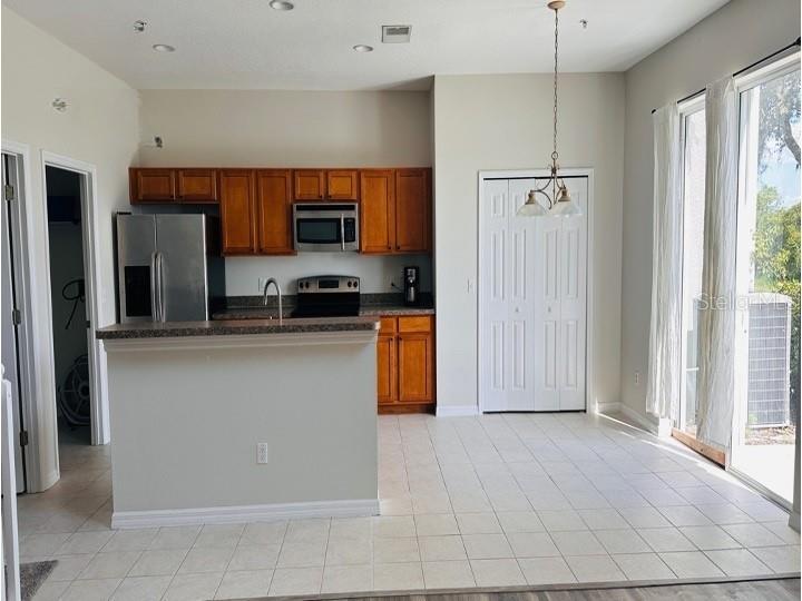A kitchen features wood cabinets, stainless steel appliances, a breakfast bar, and tile flooring — 6114 CHAPLEDALE DRIVE, ORLANDO, FL