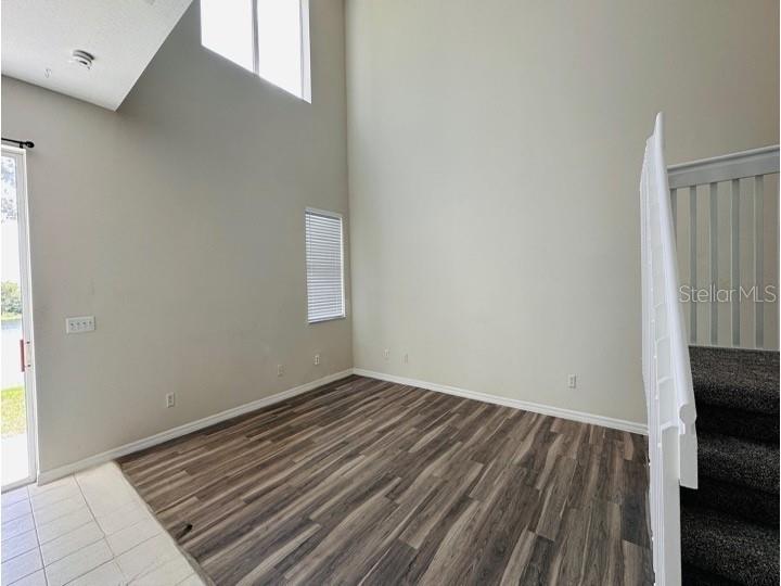 An empty room with high ceilings, wood-look flooring, and a staircase with white railings — 6114 CHAPLEDALE DRIVE, ORLANDO, FL