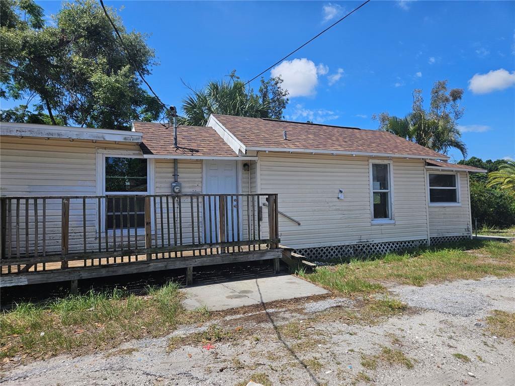A single-story house with light-colored siding, a brown shingled roof, and a wooden front deck — 2220 20TH STREET S, ST PETERSBURG, FL