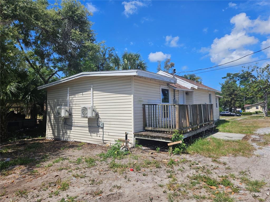A single-story house with beige vinyl siding, two wall-mounted air conditioning units, and a wooden deck — 2220 20TH STREET S, ST PETERSBURG, FL