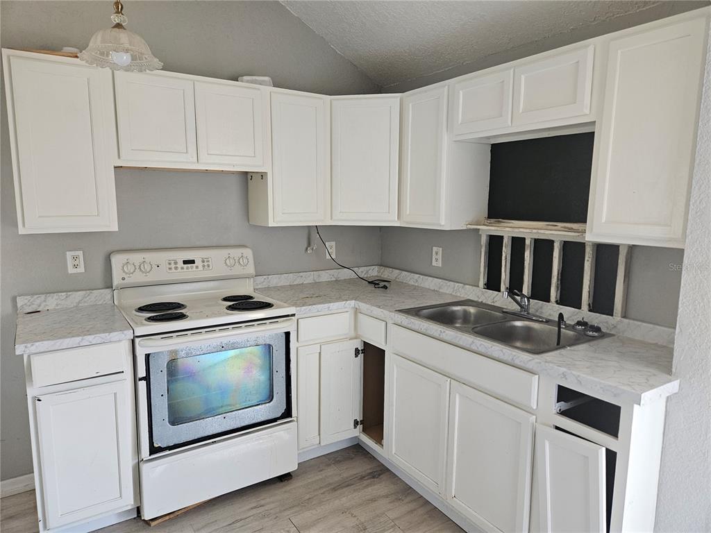 A kitchen features white cabinets, a white electric stove, and marble-patterned laminate countertops — 2220 20TH STREET S, ST PETERSBURG, FL