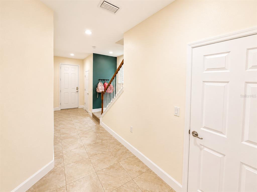 A tiled entryway features a staircase with a dark green accent wall and white doors — 6118 VOYAGERS PLACE, APOLLO BEACH, FL