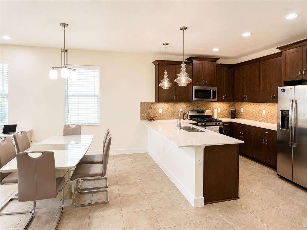 A kitchen with dark wood cabinets, white countertops, and an adjacent dining area with chairs — 6118 VOYAGERS PLACE, APOLLO BEACH, FL
