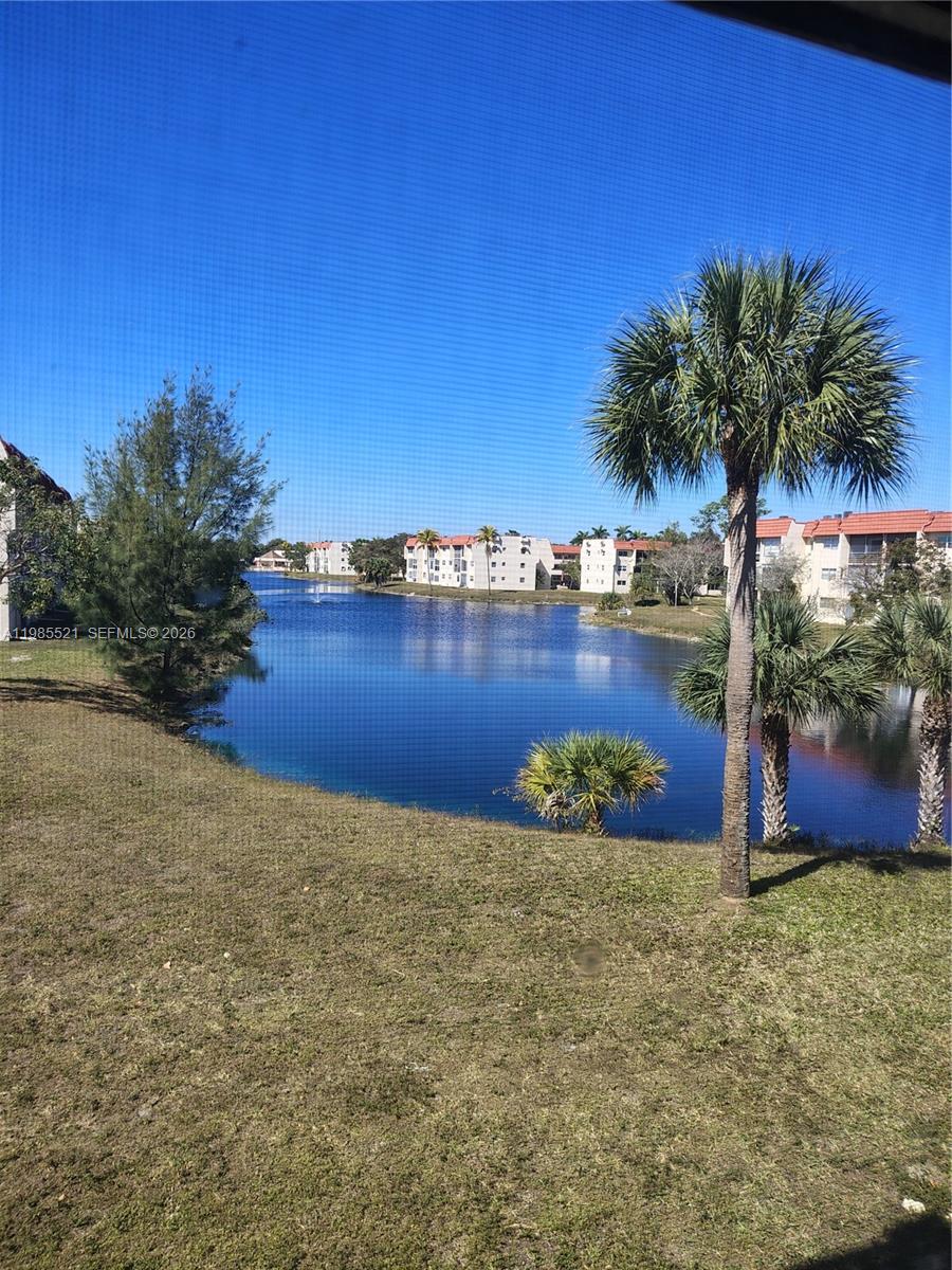 A view of a lake surrounded by apartment buildings and palm trees — 3051 E Sunrise Lakes Dr # 210, Sunrise FL 33322, SUNRISE, FL