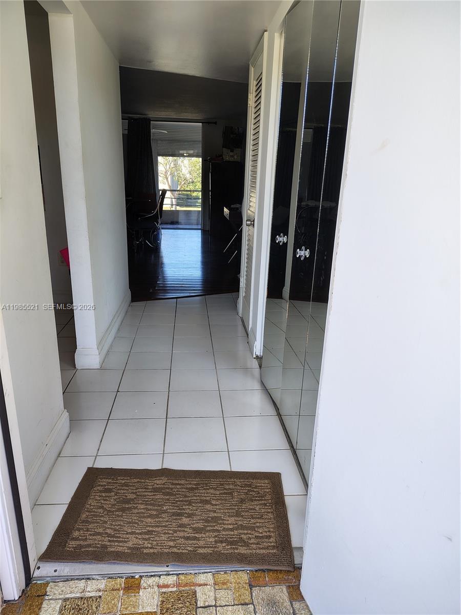 An indoor hallway features white tile flooring, a brown rug, and mirrored closet doors — 3051 E Sunrise Lakes Dr # 210, Sunrise FL 33322, SUNRISE, FL