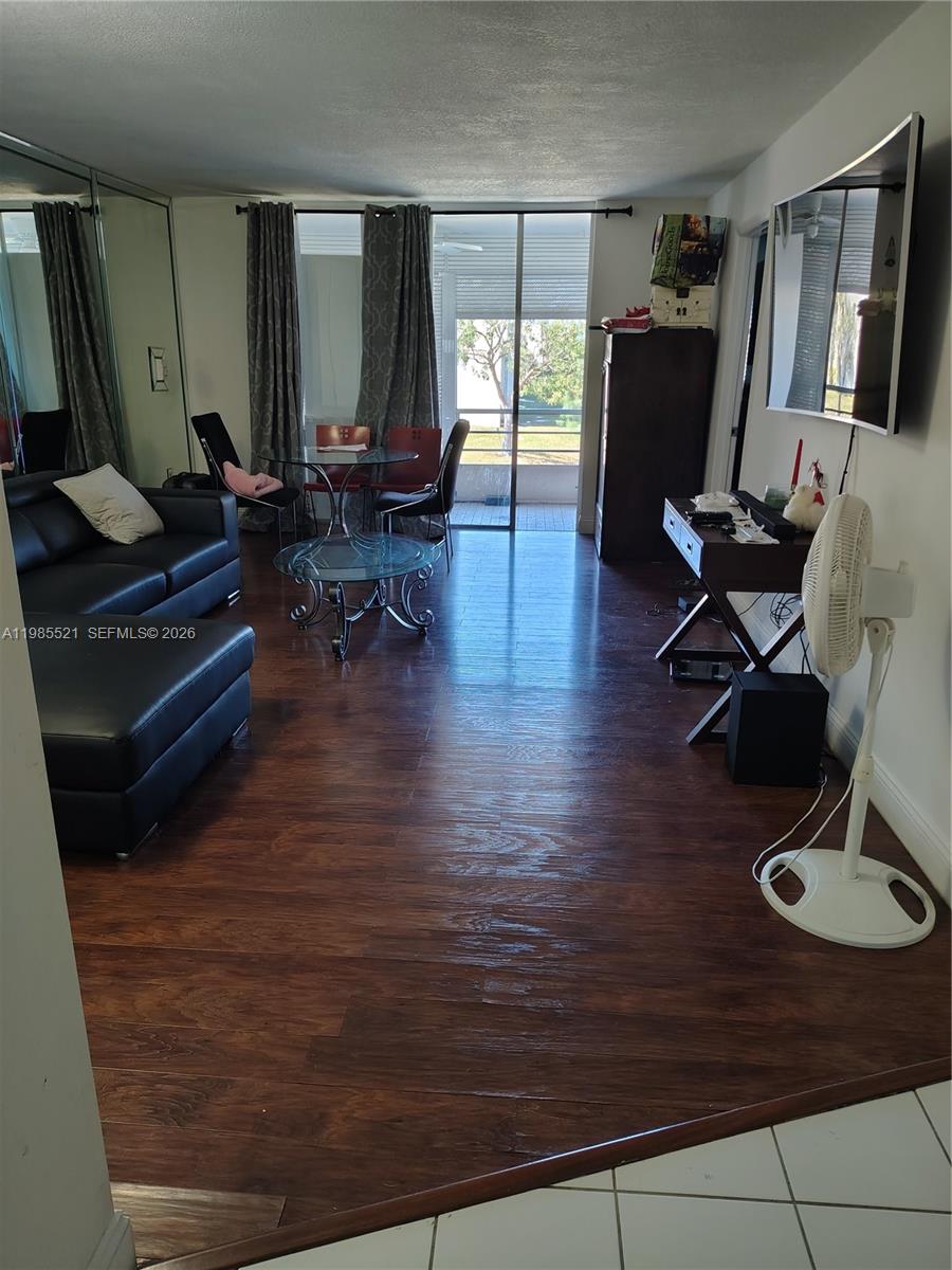 A living room features dark wood flooring, a black leather sofa, and a glass dining set — 3051 E Sunrise Lakes Dr # 210, Sunrise FL 33322, SUNRISE, FL