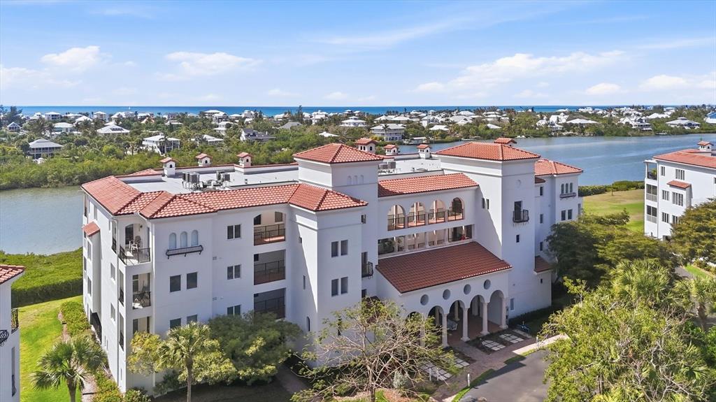 An aerial view shows a white multi-story building with a red tile roof near water — 11160 HACIENDA DEL MAR BOULEVARD UNIT D-303, PLACIDA, FL