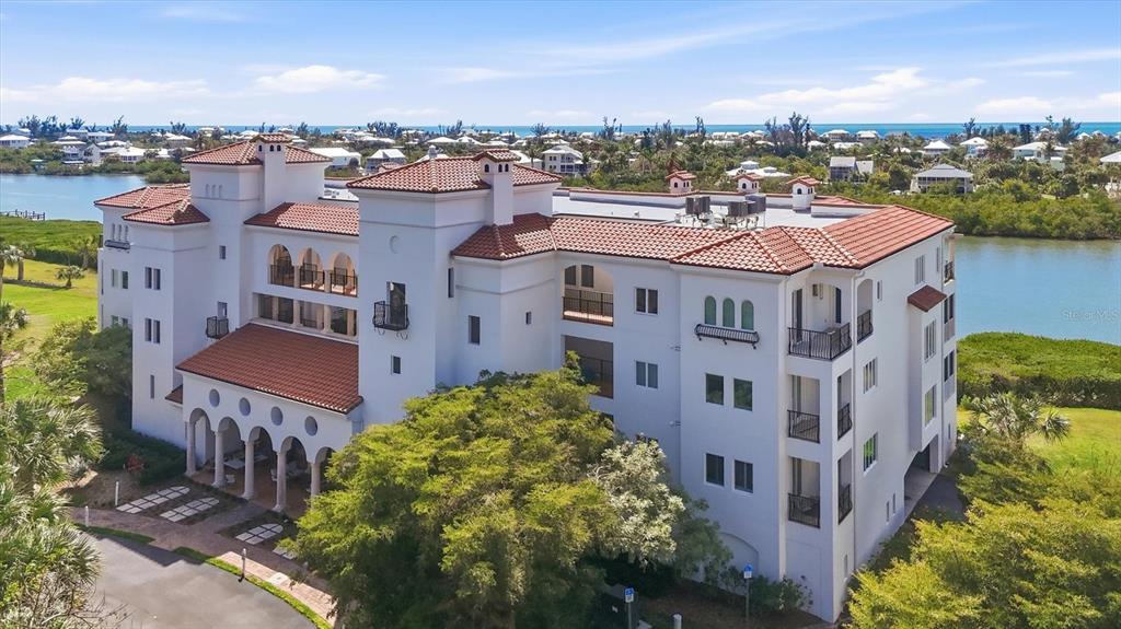 An aerial view of a multi-story white building with a red tile roof near water — 11160 HACIENDA DEL MAR BOULEVARD UNIT D-303, PLACIDA, FL