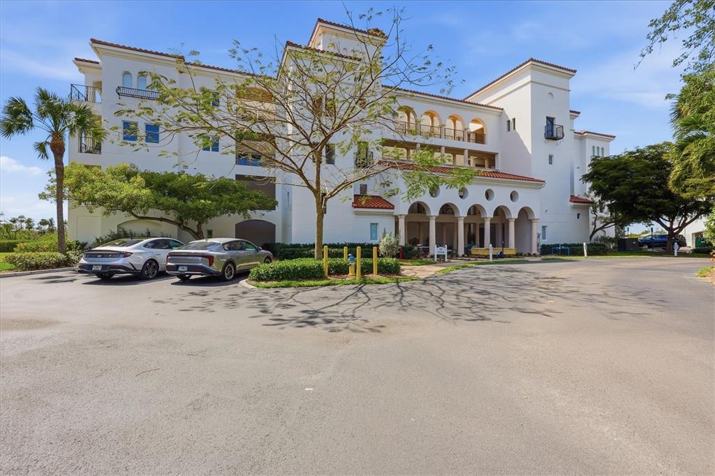 A multi-story white building with arched entryways and a parking lot in the foreground — 11160 HACIENDA DEL MAR BOULEVARD UNIT D-303, PLACIDA, FL