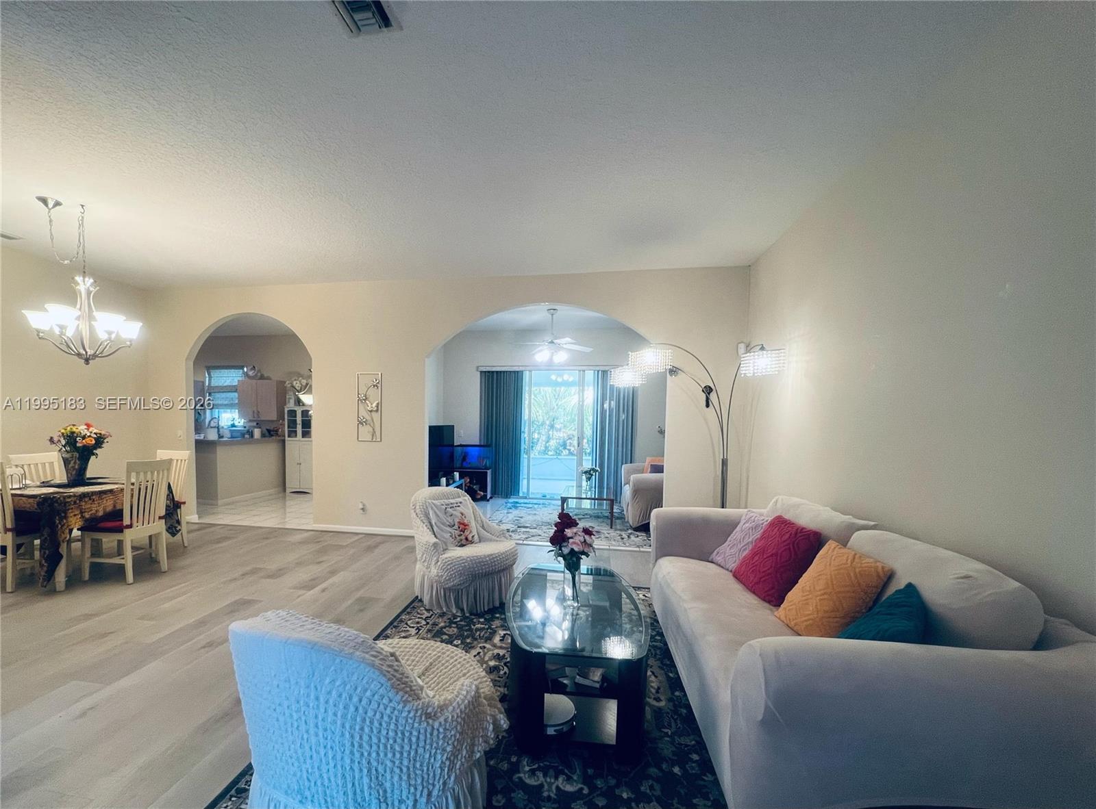 A living room and dining area feature arched doorways, light flooring, and neutral walls — 3746 Spring Crest Ct, Lake Worth FL 33467, LAKE WORTH, FL