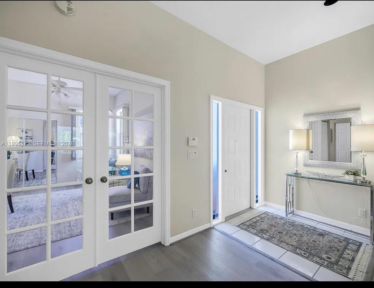 An entryway features a white front door, French doors, a console table, and tile flooring — 3746 Spring Crest Ct, Lake Worth FL 33467, LAKE WORTH, FL