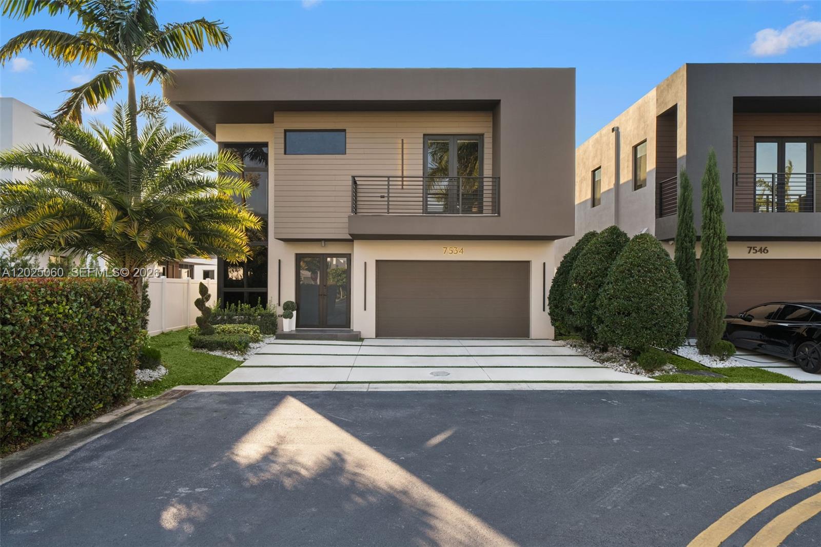 A modern two-story house features a brown garage, a balcony, and a paved driveway — 7534 NW 98th Ave, Doral FL 33178, DORAL, FL