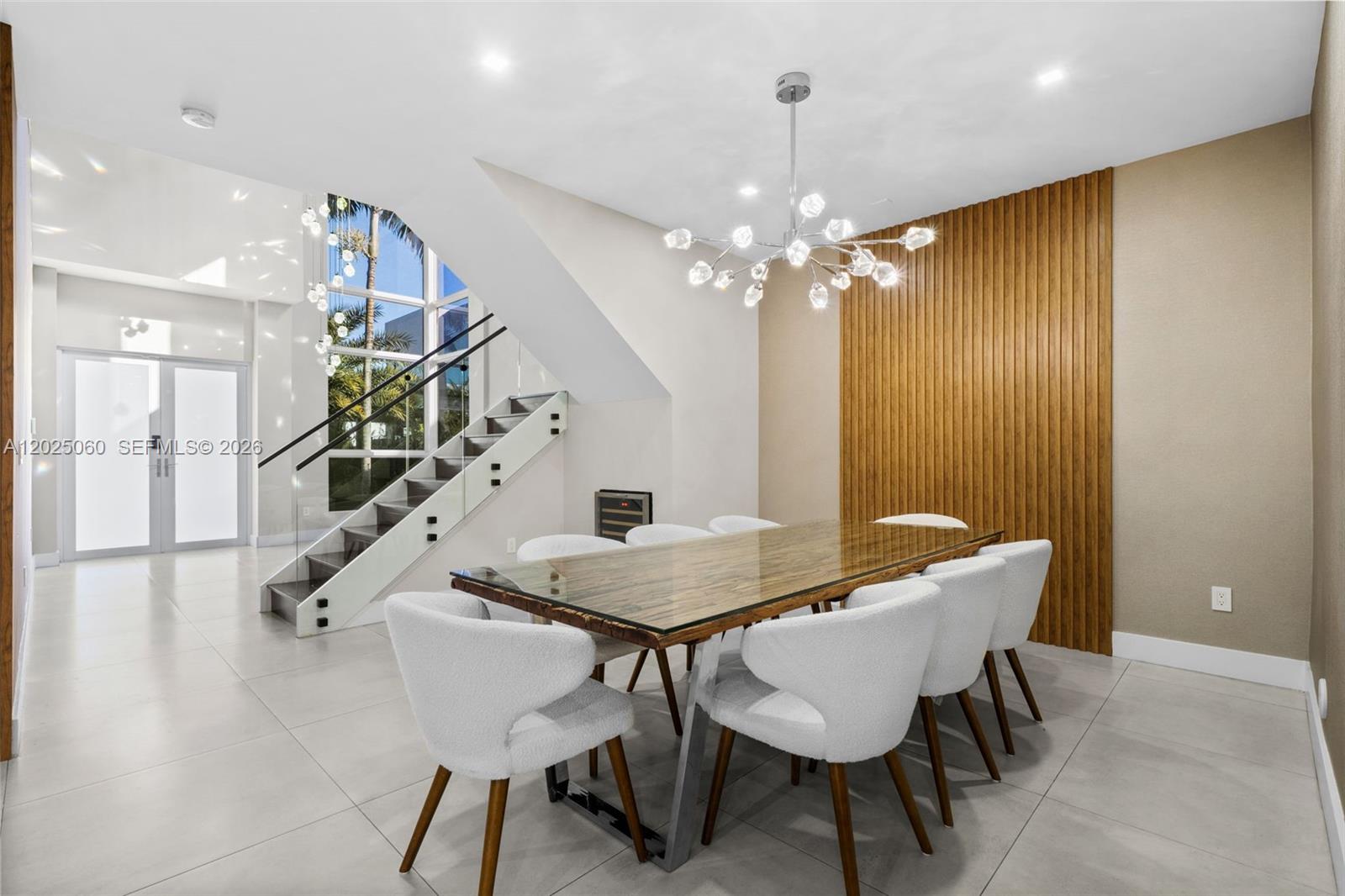 A dining room features a glass-topped table, white chairs, a wood-slatted wall, and a staircase — 7534 NW 98th Ave, Doral FL 33178, DORAL, FL