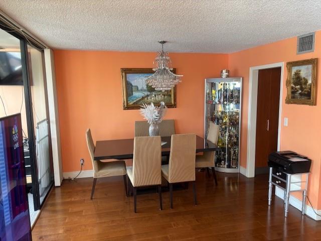 A dining room with orange walls, a crystal chandelier, a dark table, and hardwood floors — 808 Bridgewood Place # 808, Boca Raton FL 33434, BOCA RATON, FL
