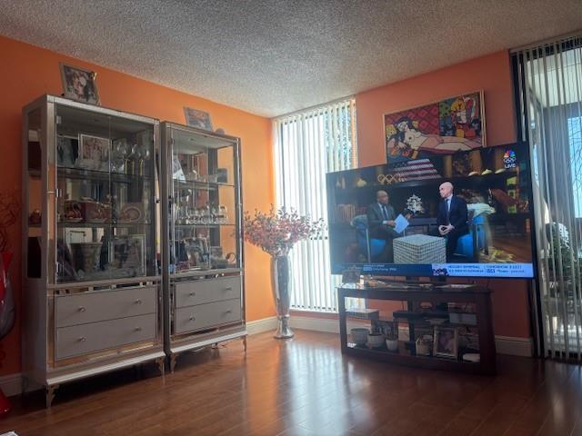 A living room with orange walls, two mirrored display cabinets, and a television on a stand — 808 Bridgewood Place # 808, Boca Raton FL 33434, BOCA RATON, FL