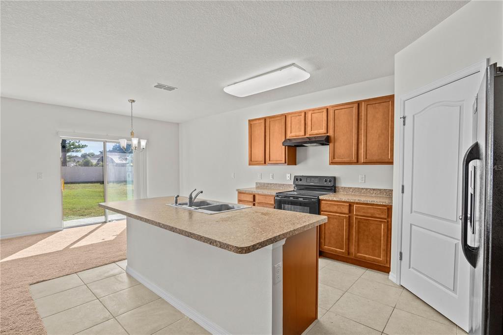 A kitchen features wood cabinets, a laminate island with a sink, and tile flooring — 817 SHEEN CIRCLE, HAINES CITY, FL