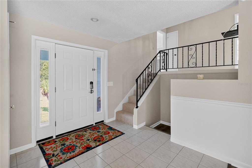 An entryway features a white front door, tiled floor, and a staircase with iron railings — 656 LITTLE WEKIVA ROAD, ALTAMONTE SPRINGS, FL