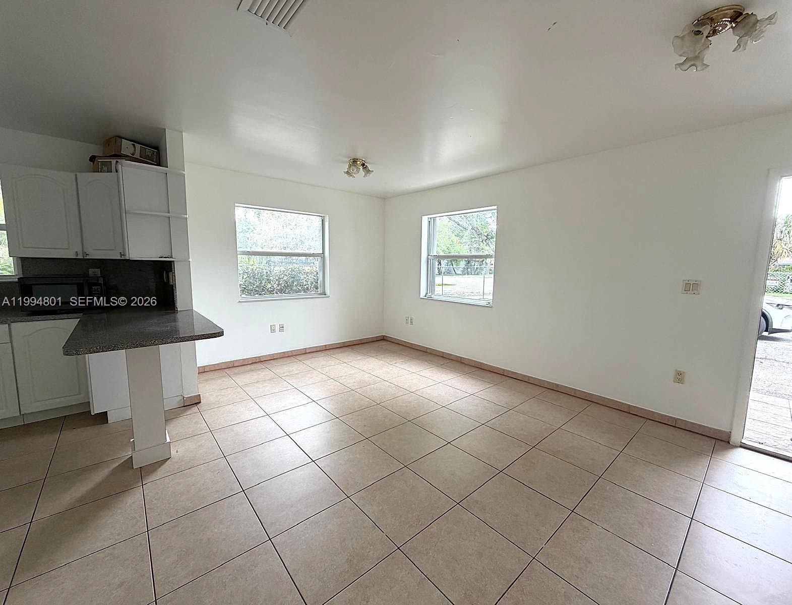 A kitchen and dining area features white cabinets, a breakfast bar, and tiled flooring — 14140 NE 2 Ct # 4, Miami FL 33161, MIAMI, FL