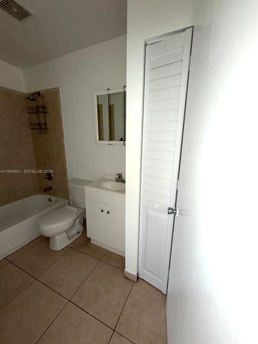 A bathroom features a white vanity, a toilet, a bathtub with tan tiles, and a closet — 14140 NE 2 Ct # 4, Miami FL 33161, MIAMI, FL