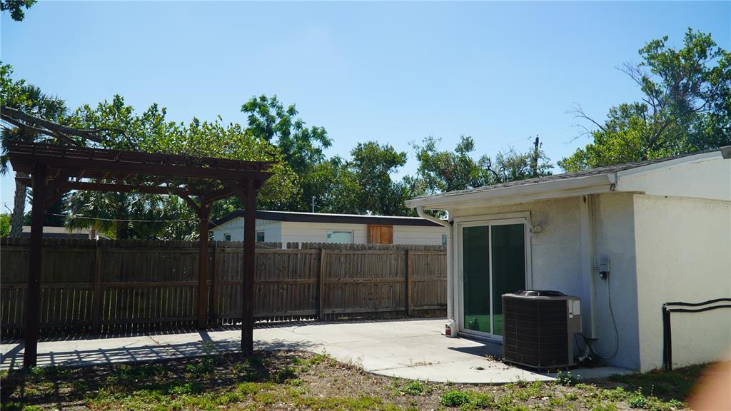 A backyard features a concrete patio, a wooden pergola, and a sliding glass door — 4111 W MONTGOMERY TERRACE, TAMPA, FL